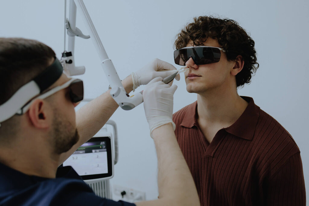 Doctor with laser and protective glasses treating a patient.