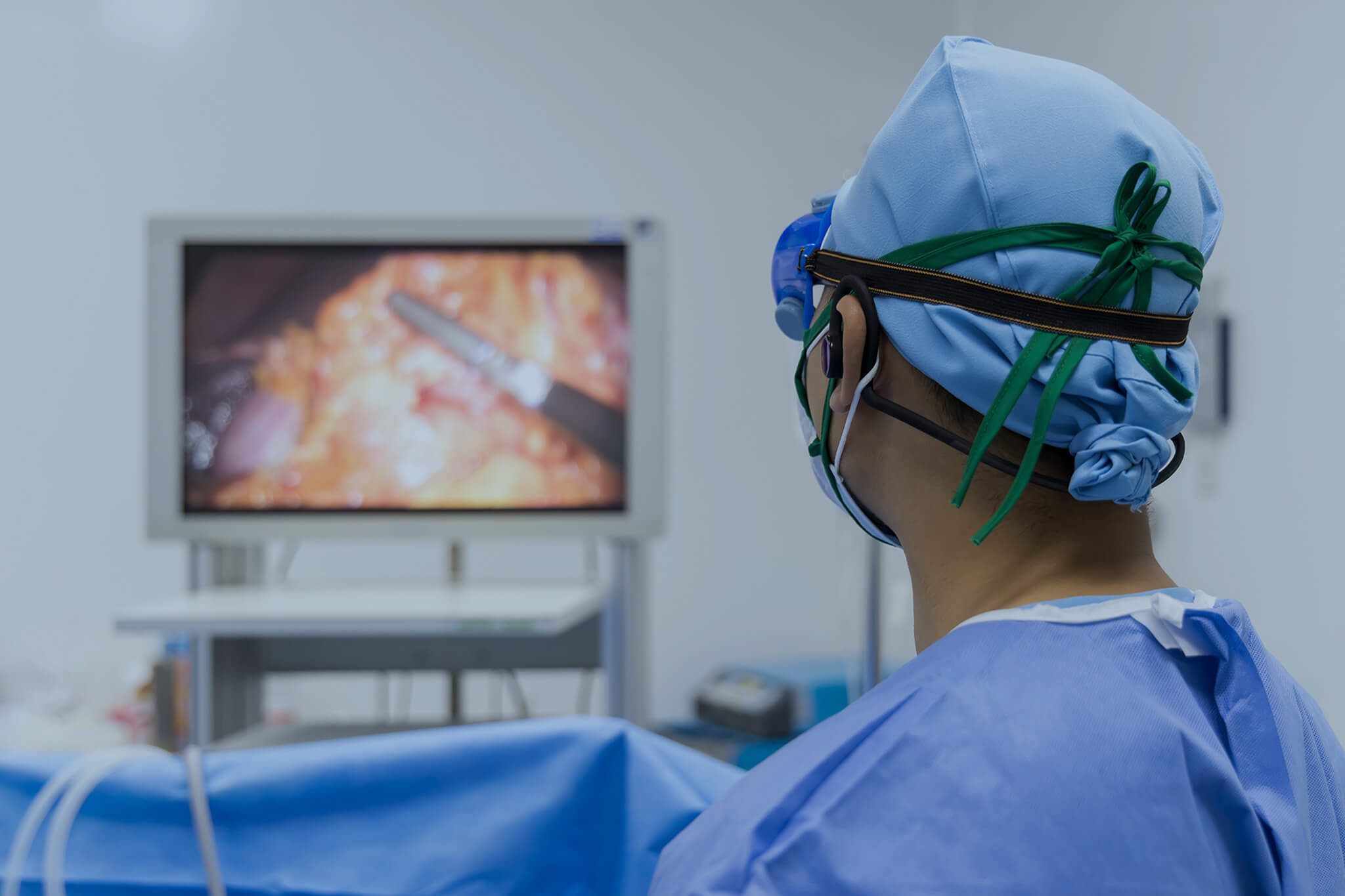 Surgeon in blue uniform looking at monitor screen in the operating room.