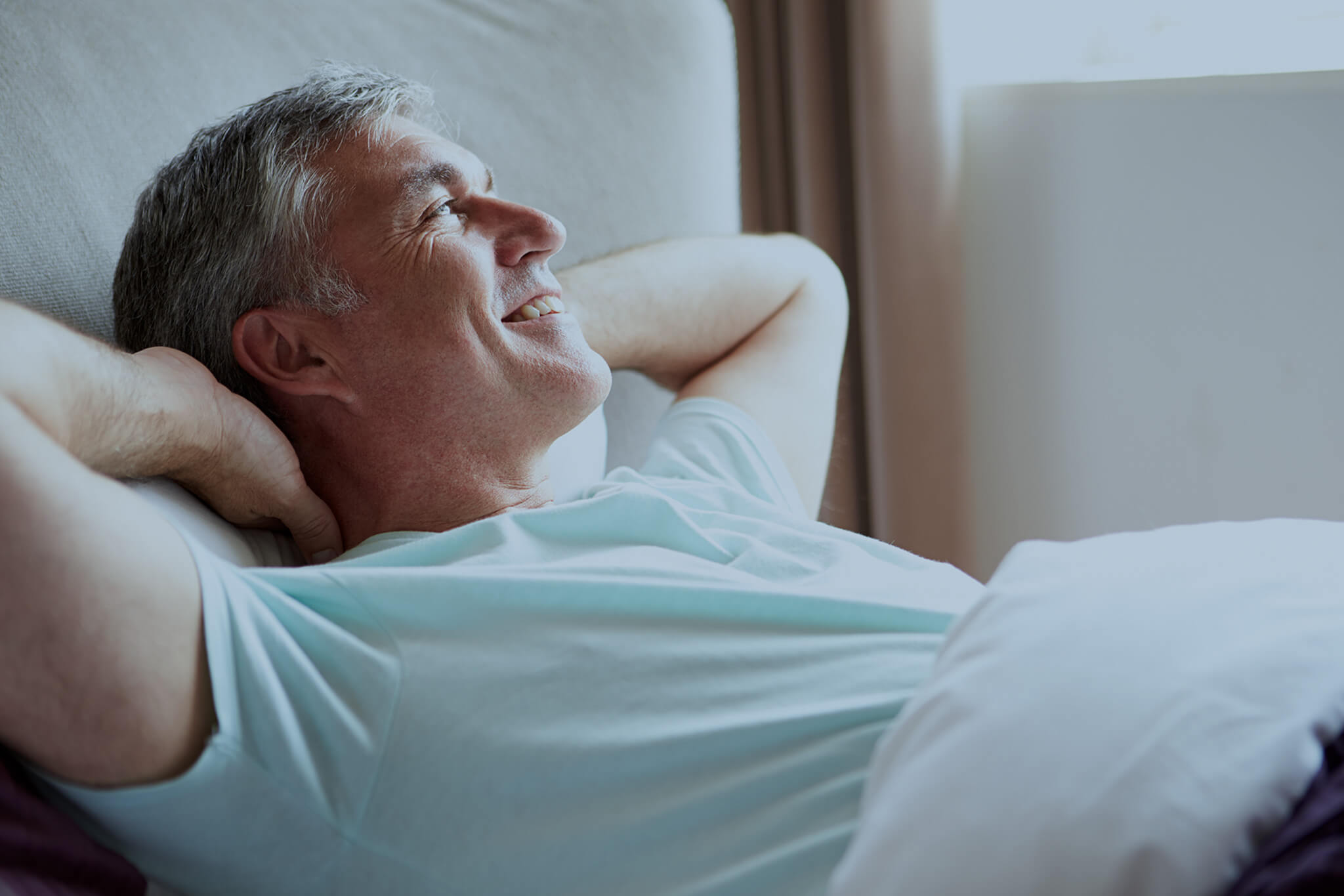 Middle aged man waking up in bed.