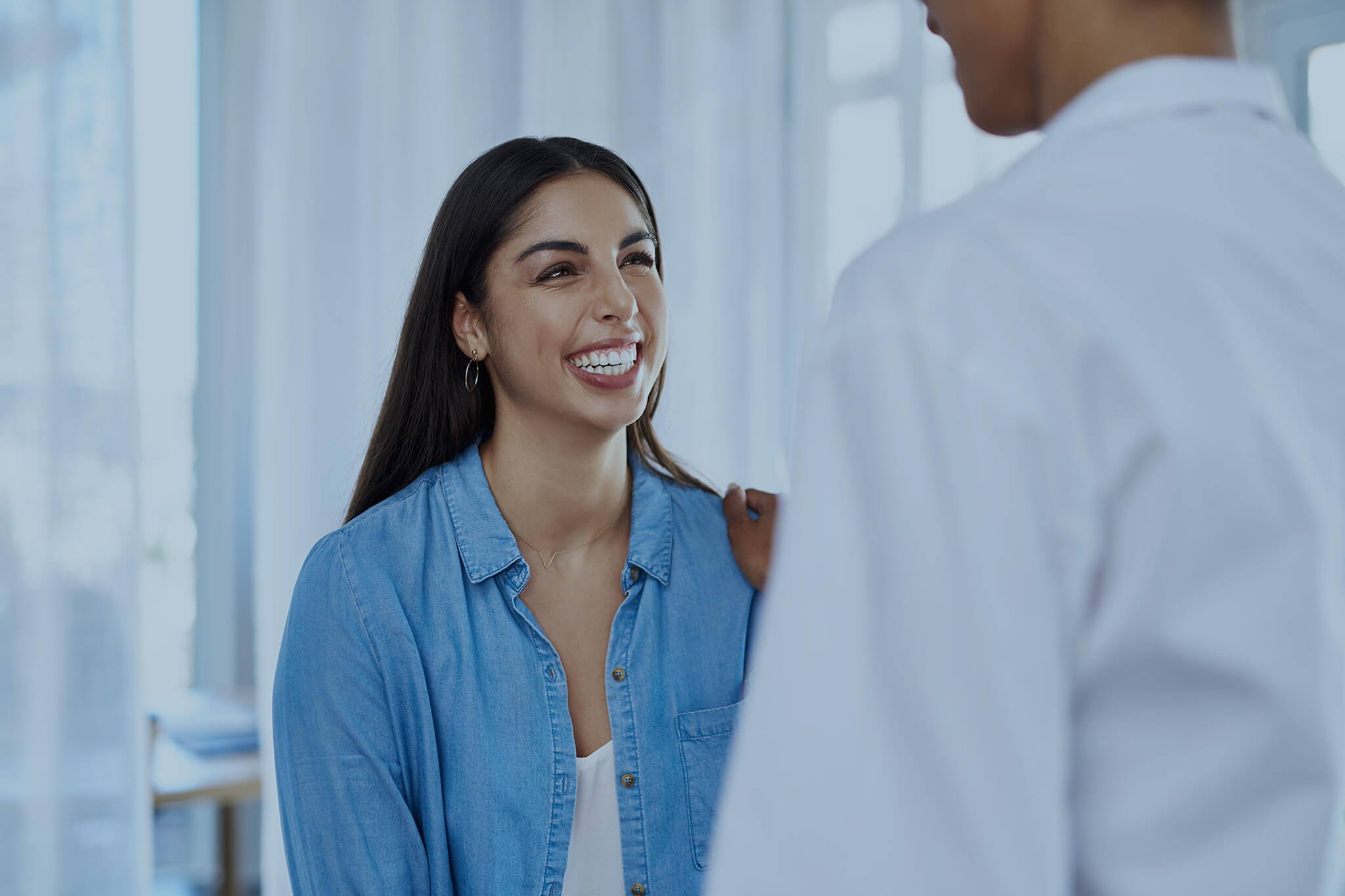 Smiling woman and doctor in office for gynecology consultation.
