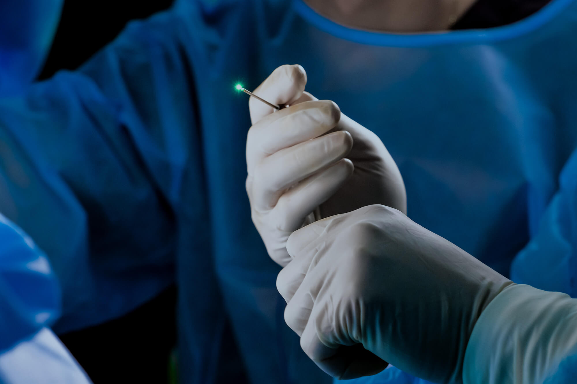 Green medical laser in the hands of a surgeon. Laser treatment of diseases.