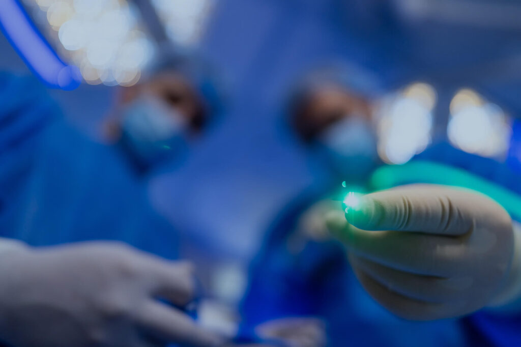 Surgical teams focus on a laser device during a procedure.