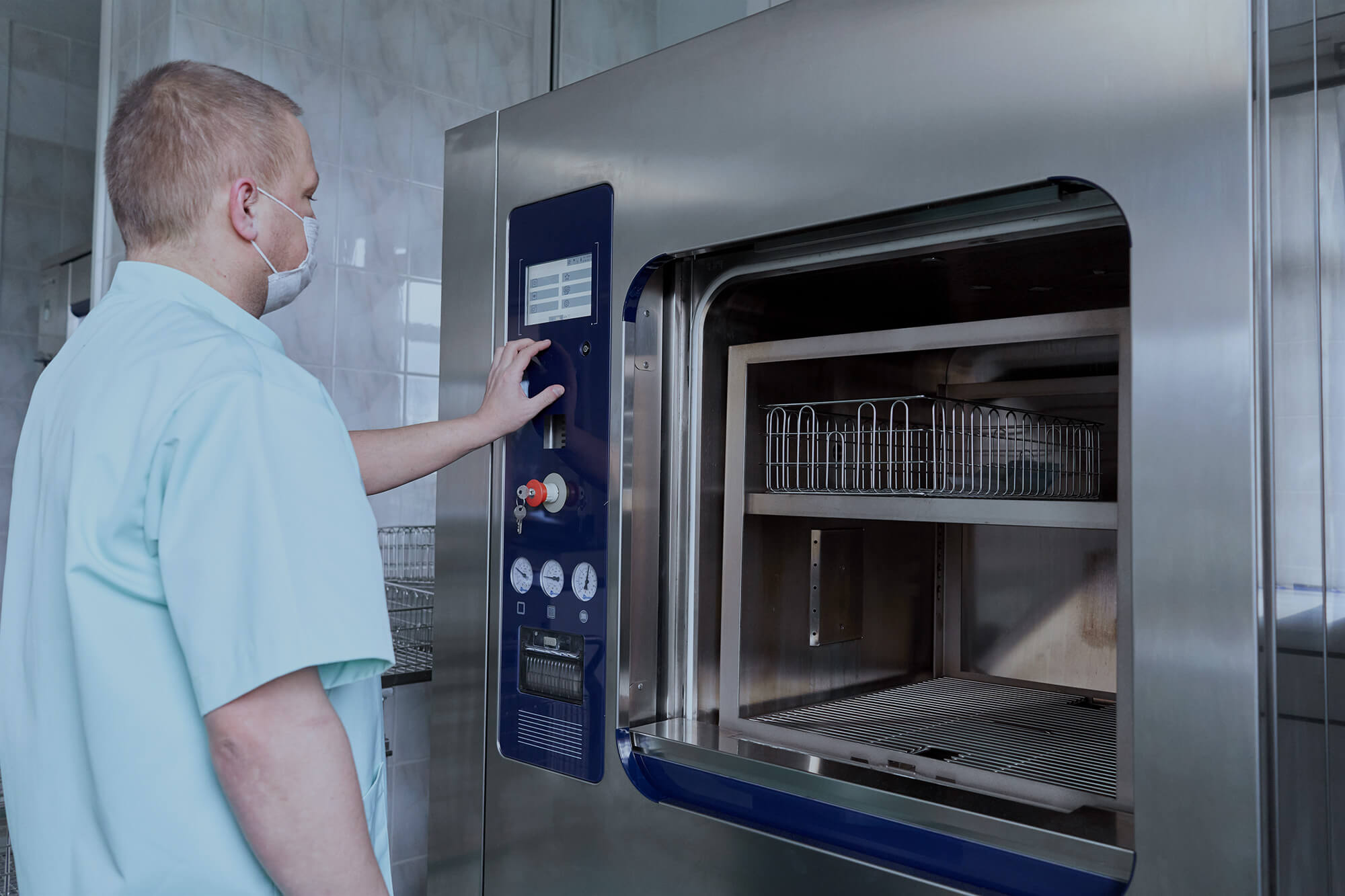 Man sterilising hospital material with a sterilisation machine.
